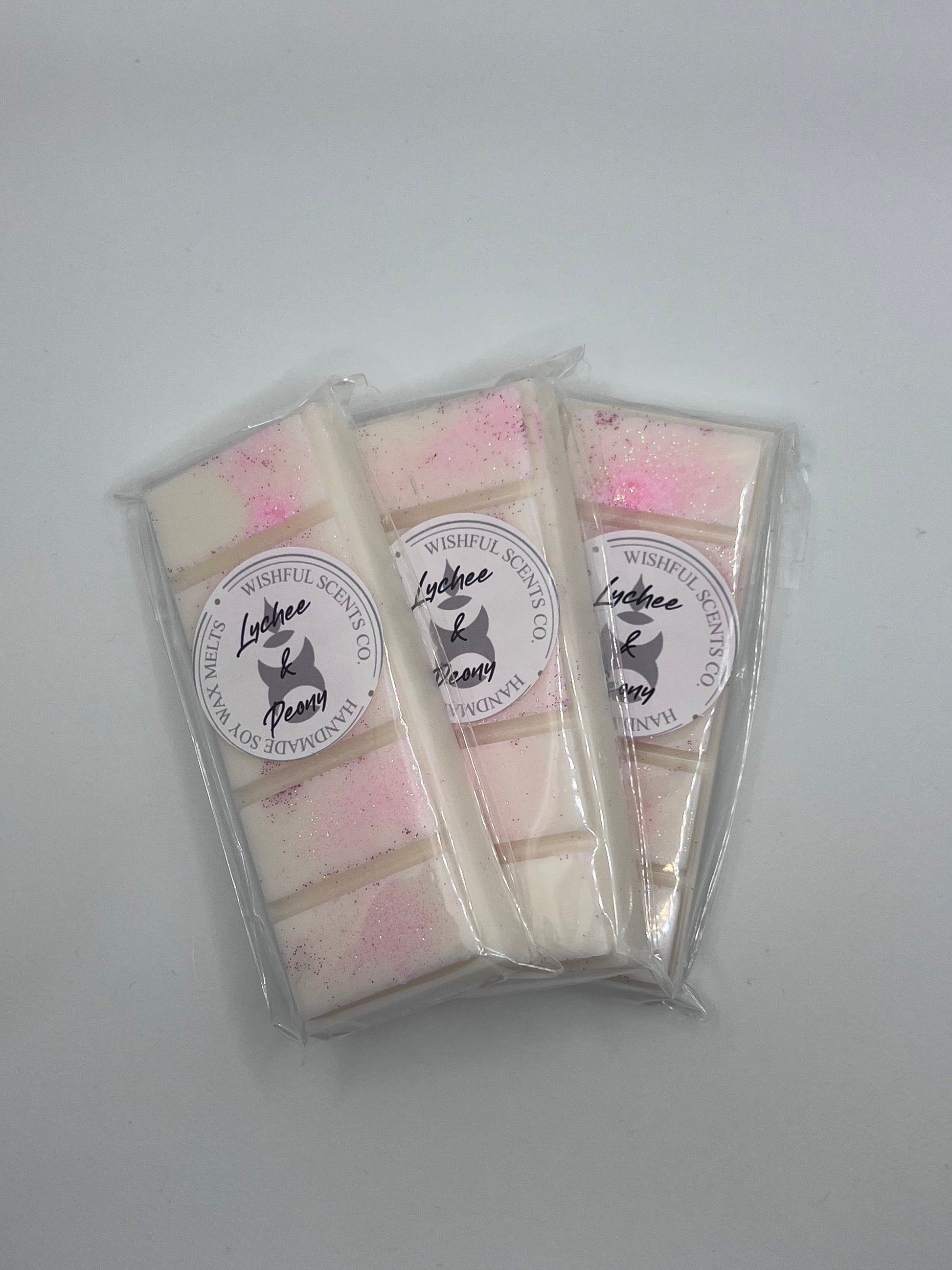 3 Lychee and Peony snap bars wrapped in clear cellophane wraps placed over each other with lychee and peony stickers on them.