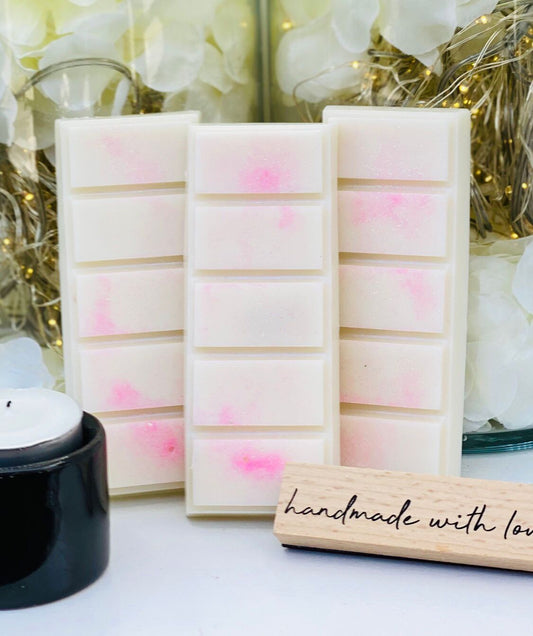 3 Lychee and Peony snap bars standing up right with a tea light candle next to it. A handmade with love sign is placed in front of the wax melts.